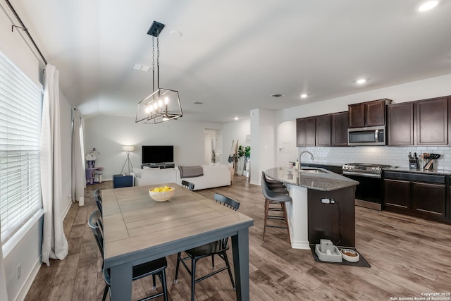 kitchen with a kitchen breakfast bar, appliances with stainless steel finishes, an island with sink, stone counters, and sink