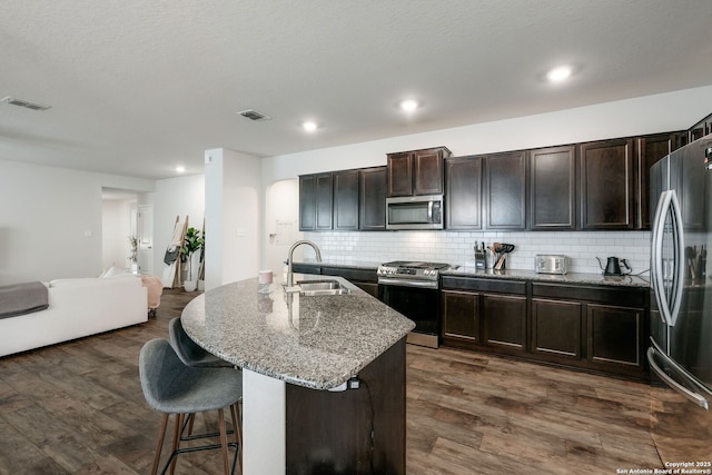 kitchen featuring an island with sink, appliances with stainless steel finishes, backsplash, and sink