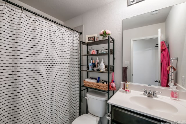 bathroom with toilet, a shower with shower curtain, vanity, and a textured ceiling