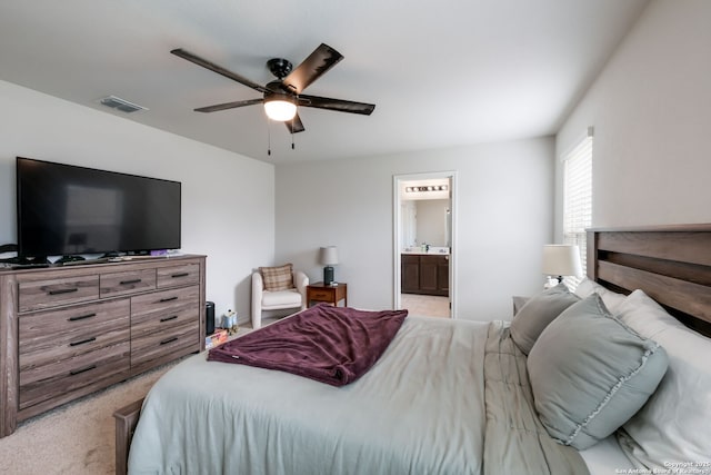 bedroom with ceiling fan, ensuite bathroom, and light carpet