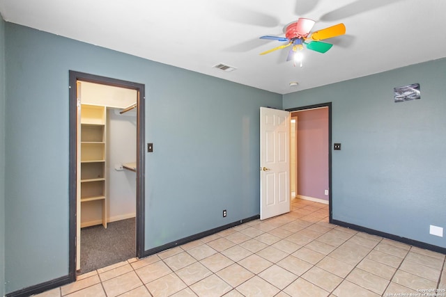 unfurnished bedroom featuring a walk in closet, a closet, and ceiling fan