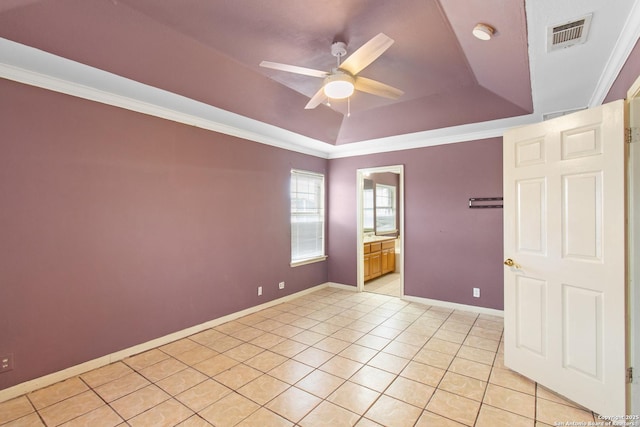 tiled empty room with ceiling fan, ornamental molding, and a raised ceiling