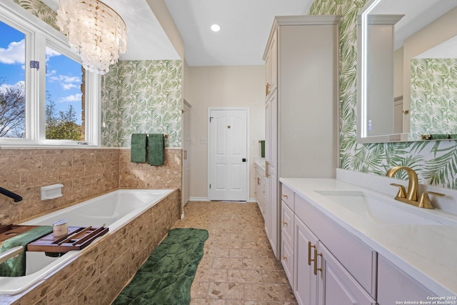 bathroom featuring vanity, a chandelier, and tiled bath