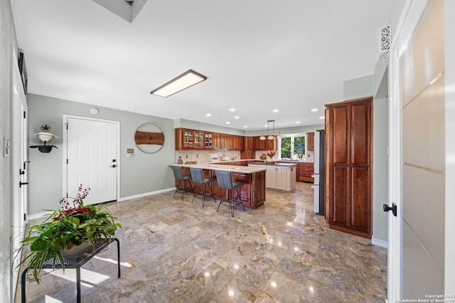 kitchen with kitchen peninsula, pendant lighting, a center island, stainless steel fridge, and a kitchen bar