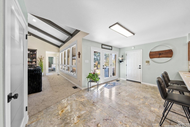 entrance foyer featuring a textured ceiling, french doors, light carpet, and beamed ceiling