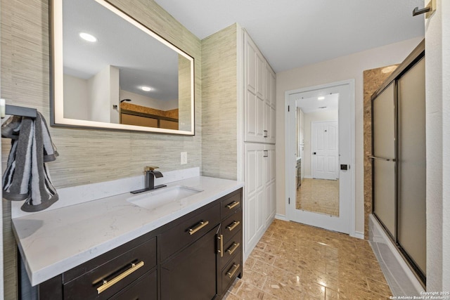 bathroom featuring backsplash, shower / bath combination with glass door, and vanity