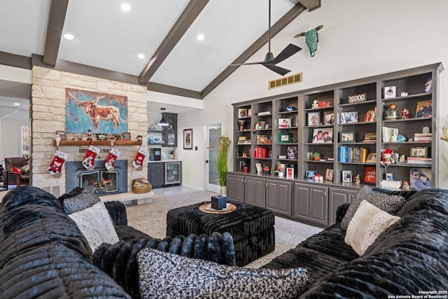 carpeted living room with high vaulted ceiling, ceiling fan, beamed ceiling, and a stone fireplace