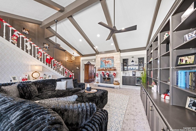 living room with lofted ceiling with beams, ceiling fan, and a stone fireplace