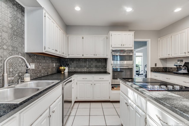 kitchen featuring stainless steel appliances, sink, white cabinets, light tile patterned floors, and tasteful backsplash