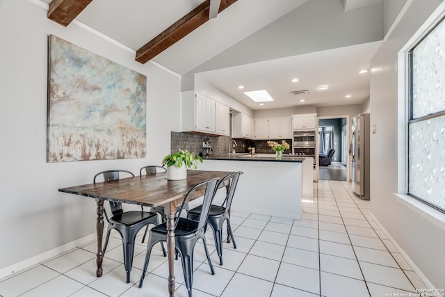 tiled dining room with lofted ceiling with skylight