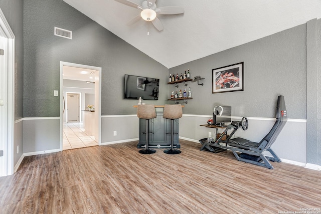 interior space featuring high vaulted ceiling, light wood-type flooring, ceiling fan, and bar