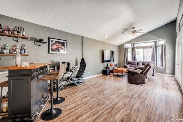 living room featuring wood-type flooring, bar, vaulted ceiling, and ceiling fan