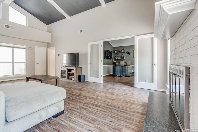 living room with hardwood / wood-style floors, a healthy amount of sunlight, french doors, high vaulted ceiling, and beam ceiling