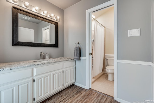 bathroom with toilet, wood-type flooring, and vanity