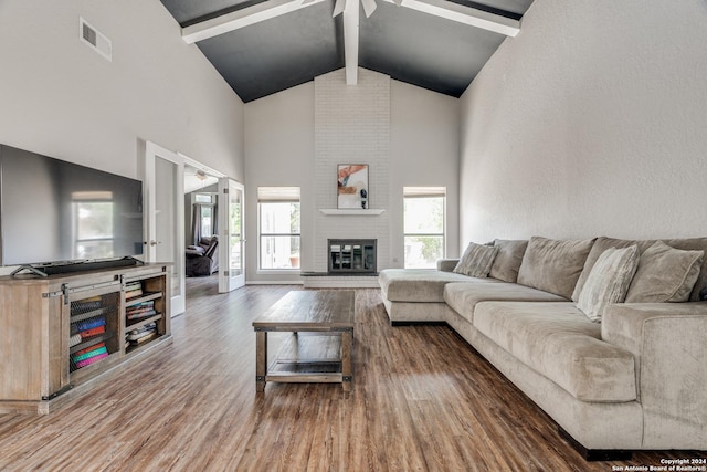 living room featuring hardwood / wood-style floors, high vaulted ceiling, beam ceiling, a fireplace, and ceiling fan