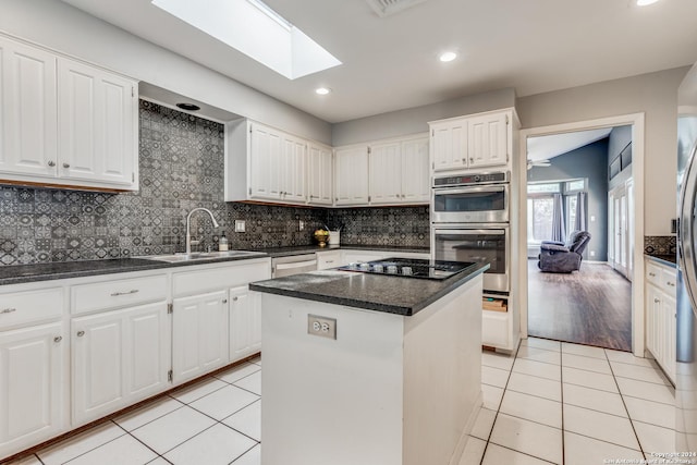 kitchen with sink, a center island, white cabinetry, a skylight, and appliances with stainless steel finishes