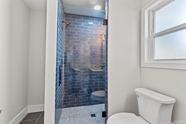 bathroom with toilet, tile patterned floors, tiled shower, and plenty of natural light