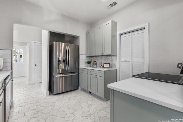 kitchen featuring tasteful backsplash, appliances with stainless steel finishes, and gray cabinetry