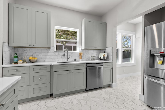 kitchen featuring tasteful backsplash, gray cabinetry, plenty of natural light, appliances with stainless steel finishes, and sink