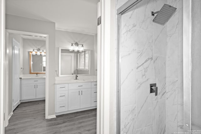 bathroom with hardwood / wood-style floors, a tile shower, and vanity