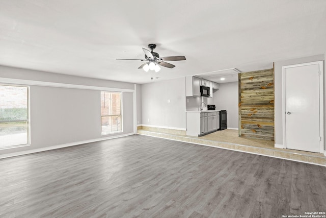 unfurnished living room with sink, light wood-type flooring, and ceiling fan