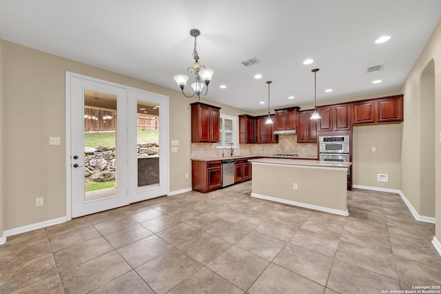 kitchen featuring stainless steel appliances, a center island, a notable chandelier, pendant lighting, and decorative backsplash