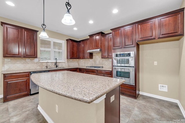 kitchen with light stone countertops, a center island, hanging light fixtures, stainless steel appliances, and sink