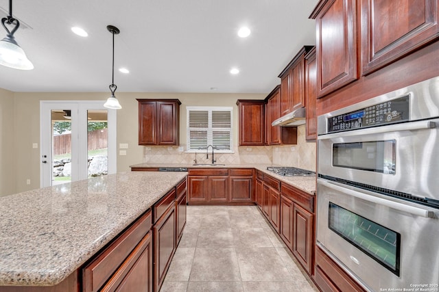 kitchen featuring sink, stainless steel appliances, decorative light fixtures, and a kitchen island