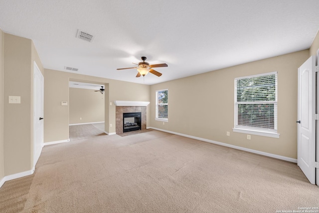 unfurnished living room featuring a fireplace, light colored carpet, and a wealth of natural light