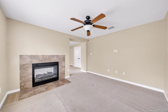 unfurnished living room with ceiling fan, light colored carpet, and a tile fireplace