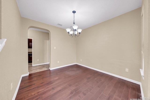 empty room featuring an inviting chandelier and dark hardwood / wood-style floors