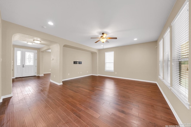 unfurnished room with ceiling fan, plenty of natural light, and dark wood-type flooring