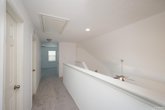 hall with lofted ceiling, a textured ceiling, and light colored carpet