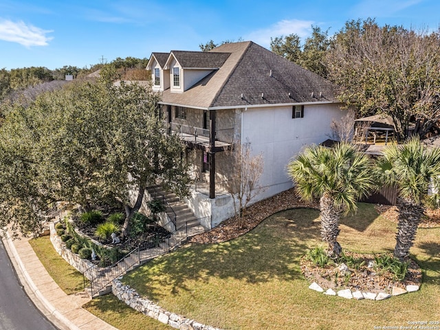 view of home's exterior featuring a balcony and a yard