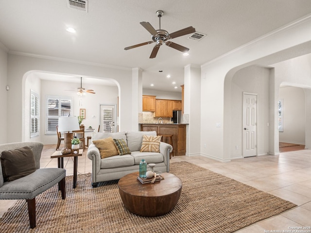 living room with sink, ceiling fan, light tile patterned floors, and crown molding