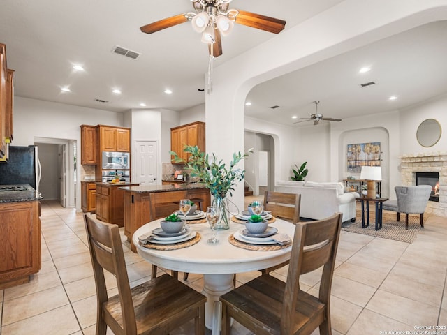 tiled dining room featuring a fireplace and ceiling fan