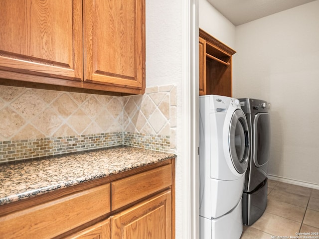 laundry room with light tile patterned flooring, washing machine and clothes dryer, and cabinets