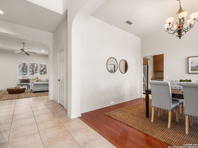 tiled dining room with ceiling fan with notable chandelier