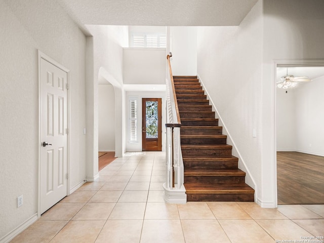 tiled entryway featuring a high ceiling and ceiling fan