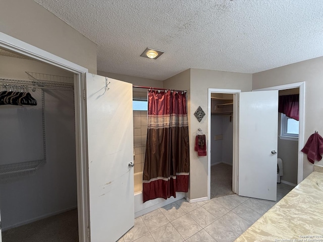 bathroom with shower / tub combo with curtain, a healthy amount of sunlight, tile patterned floors, and a textured ceiling