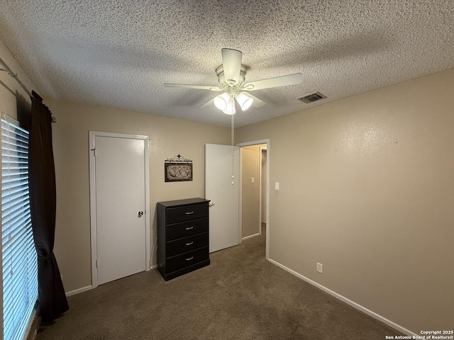 unfurnished bedroom with ceiling fan, a textured ceiling, and dark colored carpet