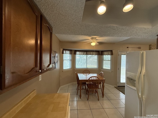 unfurnished dining area featuring ceiling fan, light tile patterned floors, and a textured ceiling