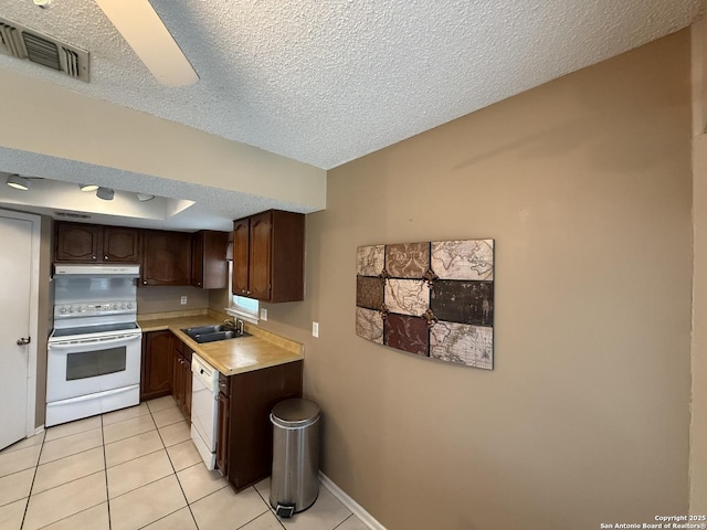 kitchen featuring sink, light tile patterned floors, white appliances, dark brown cabinetry, and a textured ceiling