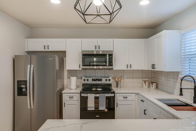 kitchen with sink, stainless steel appliances, white cabinetry, and light stone countertops