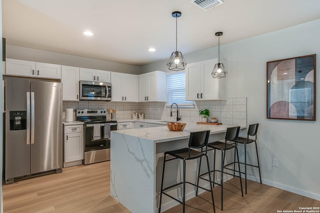 kitchen featuring white cabinets, stainless steel appliances, and pendant lighting