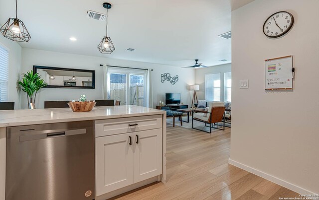 kitchen featuring decorative light fixtures, white cabinets, dishwasher, and light stone countertops