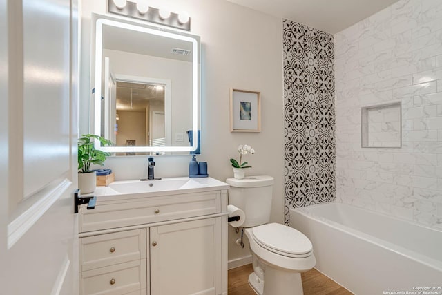 full bathroom with toilet, hardwood / wood-style flooring, tiled shower / bath, and vanity