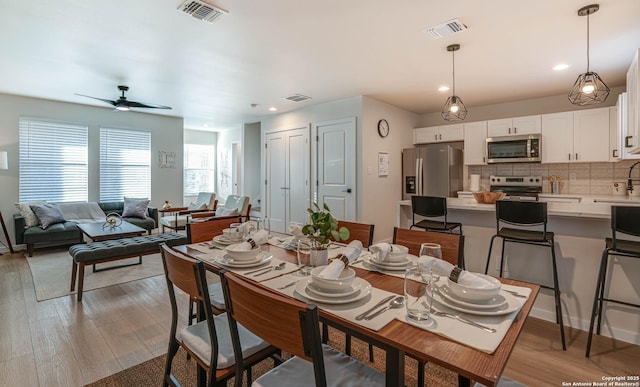 dining space with ceiling fan and light hardwood / wood-style flooring