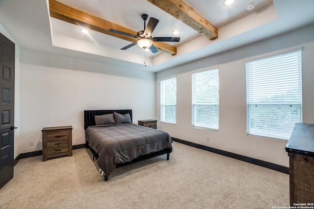 bedroom featuring ceiling fan, light carpet, beam ceiling, and a tray ceiling