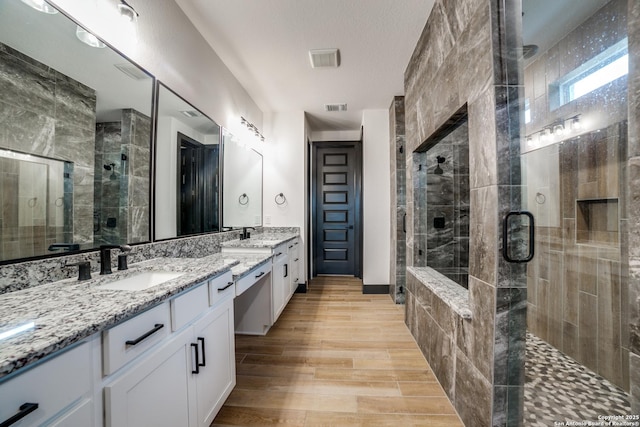 bathroom featuring hardwood / wood-style flooring, vanity, and an enclosed shower